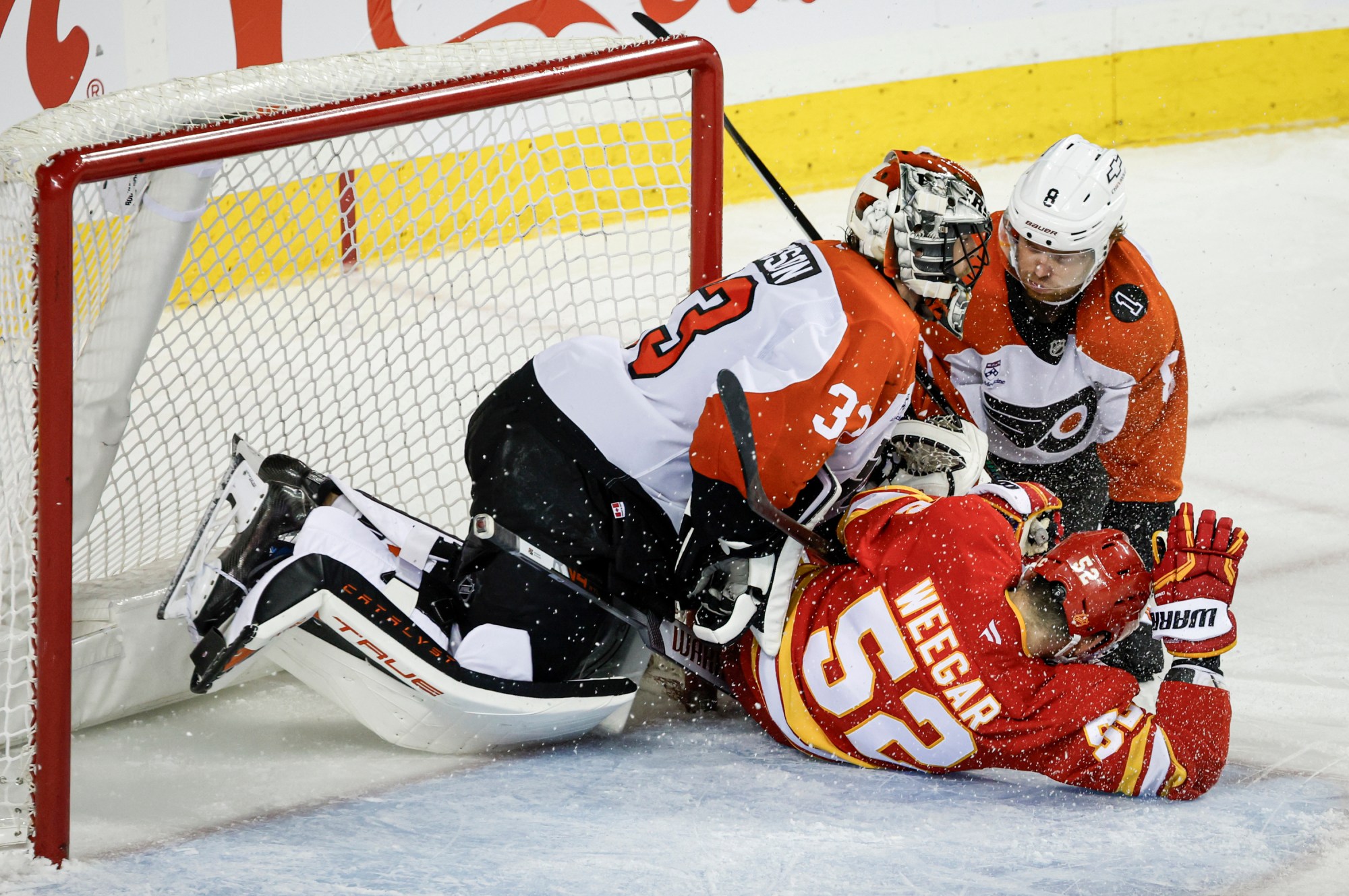 Philadelphia Flyers’ Cam York, right, and Calgary Flames’ MacKenzie Weegar, centre, crash into goalie Samuel Ersson during third period NHL hockey action in Calgary on Wednesday, Dec. 31, 2025. (Jeff McIntosh/The Canadian Press via AP)
